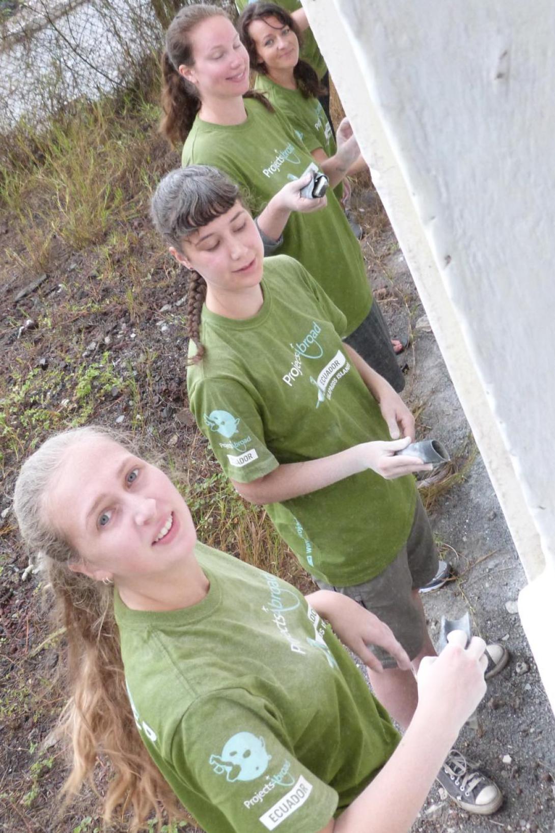 Volunteers in Ecuador helping to paint a wall with Projects Abroad Ecuador volunteer group painting a wall